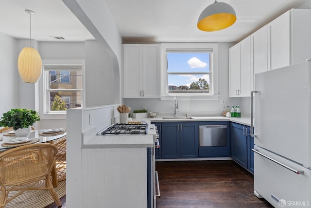 kitchen featuring decorative light fixtures, sink, white cabinets, white refrigerator, and blue cabinetry