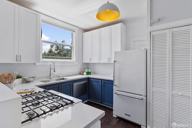 kitchen with blue cabinetry, sink, white cabinetry, decorative light fixtures, and refrigerator