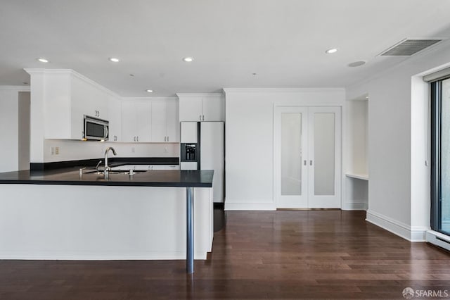 kitchen featuring white cabinets, kitchen peninsula, crown molding, dark hardwood / wood-style floors, and sink