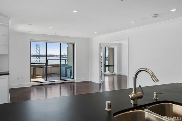 kitchen with dark hardwood / wood-style flooring, ornamental molding, sink, and a water view