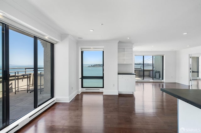 unfurnished living room featuring crown molding, a water view, dark hardwood / wood-style flooring, and a baseboard radiator