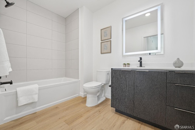 full bathroom featuring tiled shower / bath, vanity, wood-type flooring, and toilet