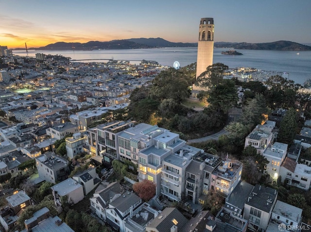 aerial view at dusk featuring a water and mountain view