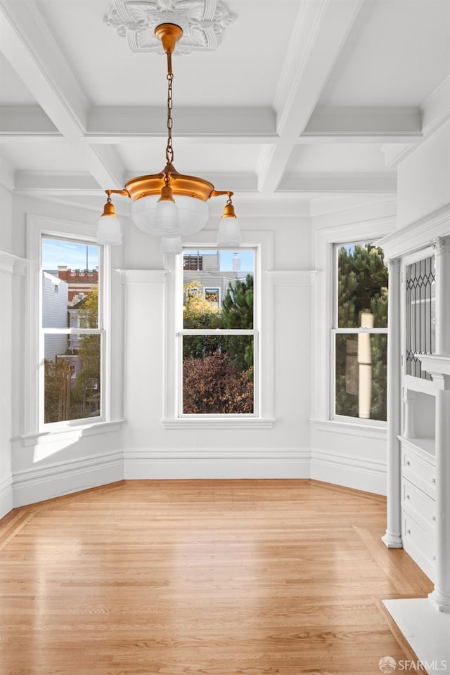 unfurnished dining area featuring coffered ceiling, beam ceiling, and light wood-type flooring