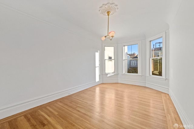 empty room with an inviting chandelier and light hardwood / wood-style flooring