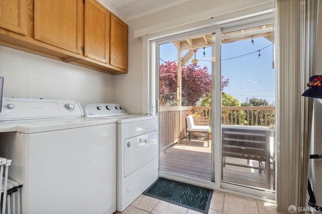 laundry room with crown molding, light tile patterned floors, washing machine and clothes dryer, and cabinets