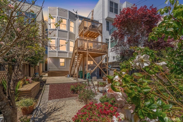 back house at dusk with a balcony and a patio