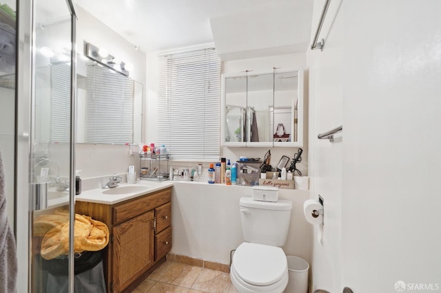 bathroom featuring vanity, tile patterned flooring, toilet, and an enclosed shower