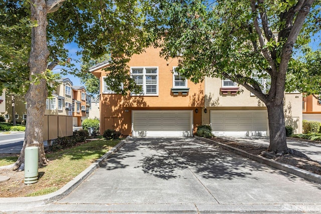 3587 Fitzsimmons Cmn, Fremont, CA 94538 - townhome / multi-family property featuring driveway, stucco siding, a garage, and a residential view