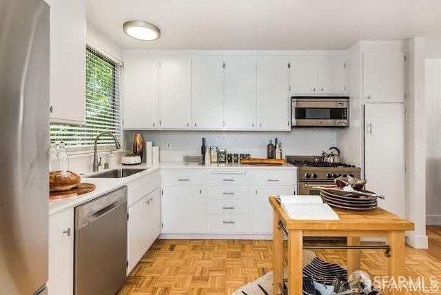 kitchen featuring stainless steel appliances, light countertops, white cabinets, and a sink