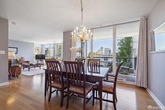 dining space with a baseboard heating unit, hardwood / wood-style floors, a notable chandelier, and a wall of windows