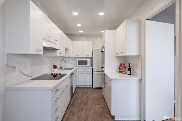 kitchen with sink, white cabinetry, appliances with stainless steel finishes, dark hardwood / wood-style flooring, and backsplash