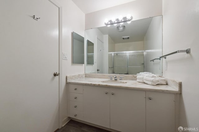 bathroom with a shower with door and vanity