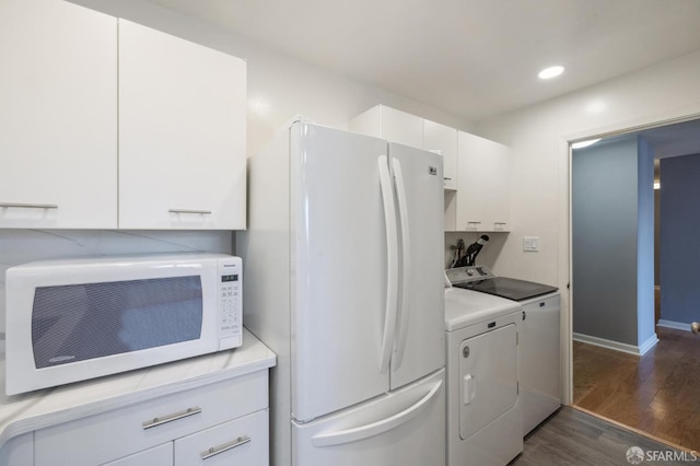 washroom with cabinets, dark wood-type flooring, and washing machine and clothes dryer