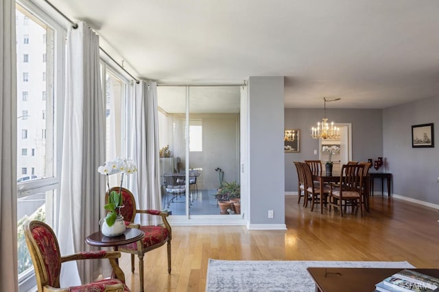 sitting room featuring a notable chandelier, a wealth of natural light, and light wood-type flooring