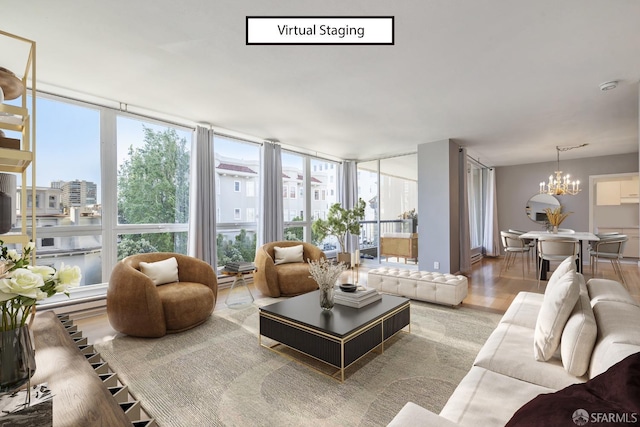 living room with an inviting chandelier, a wall of windows, and light hardwood / wood-style floors