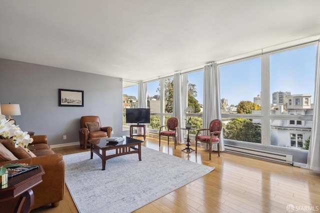 living room with floor to ceiling windows, light hardwood / wood-style floors, and a baseboard heating unit