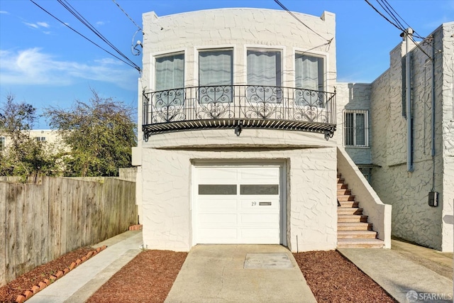 view of front of home featuring stucco siding, driveway, fence, a balcony, and stairs