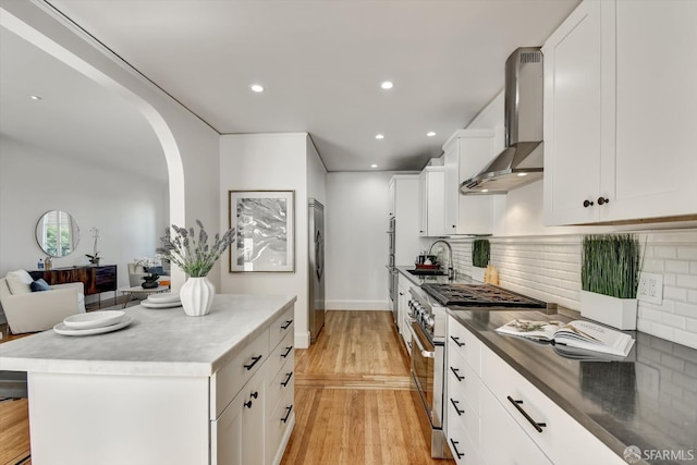 224 Twin Peaks Blvd, San Francisco, CA 94114 - kitchen with stainless steel appliances, wall chimney range hood, arched walkways, light wood-style floors, and recessed lighting