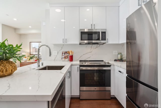 kitchen featuring light stone counters, stainless steel appliances, white cabinetry, dark hardwood / wood-style floors, and sink