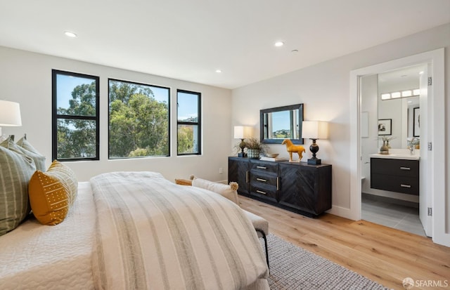 bedroom with connected bathroom and light wood-type flooring