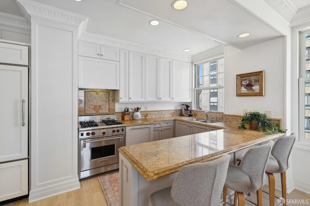 kitchen featuring premium stove, white cabinets, a kitchen breakfast bar, and kitchen peninsula