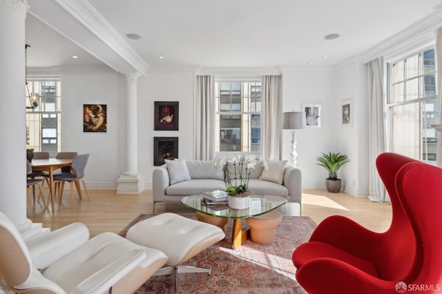 living room featuring crown molding, decorative columns, and light wood-type flooring