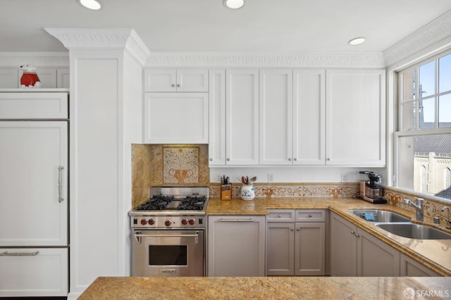 kitchen featuring tasteful backsplash, sink, luxury stove, and white cabinets