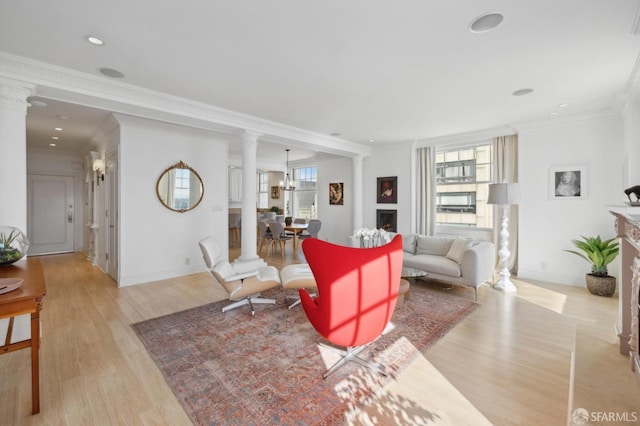 living room featuring ornate columns, ornamental molding, and light hardwood / wood-style flooring