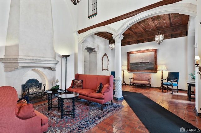 living room with a towering ceiling, a fireplace, and decorative columns