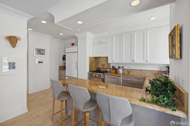 kitchen with high quality appliances, white cabinetry, ornamental molding, and kitchen peninsula