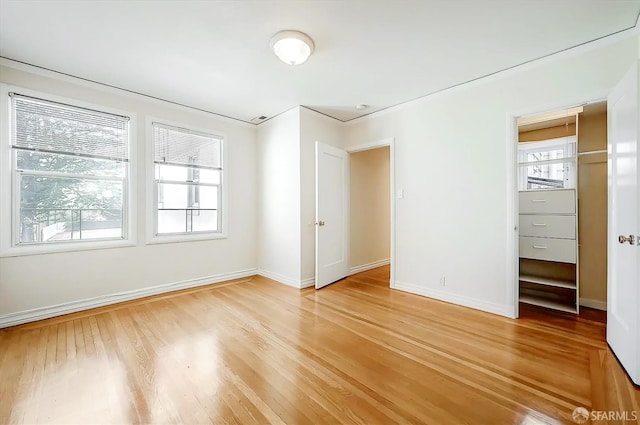 unfurnished bedroom featuring baseboards, multiple windows, and light wood-style floors