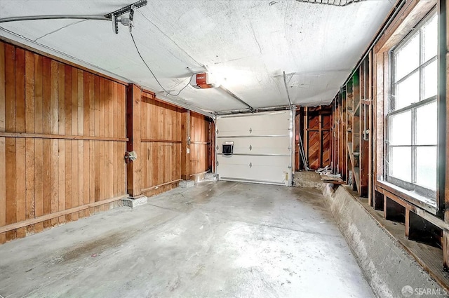 garage with a garage door opener and wood walls