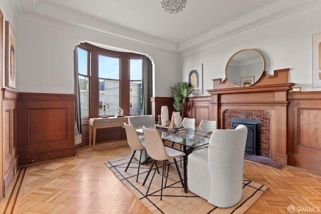 dining room with crown molding, light parquet flooring, and a brick fireplace