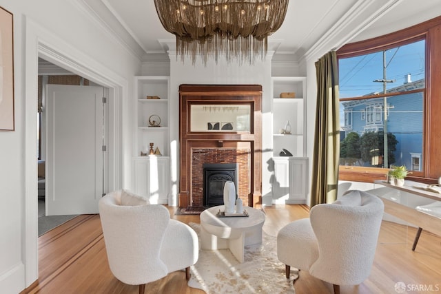 living area featuring a notable chandelier, crown molding, built in features, and light wood-type flooring