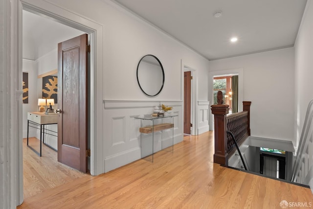 hallway featuring ornamental molding and light hardwood / wood-style floors