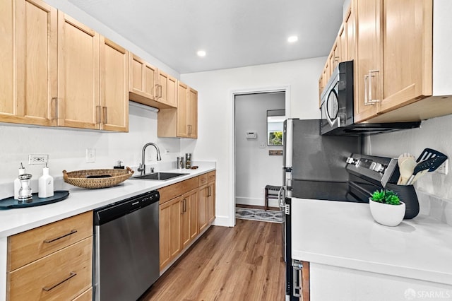 kitchen with light brown cabinetry, sink, stainless steel dishwasher, and light wood-type flooring