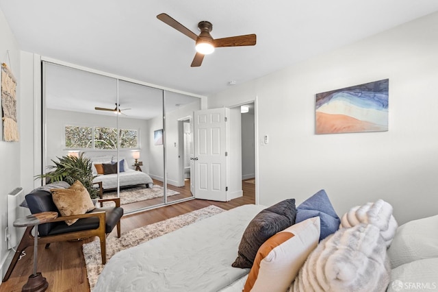 bedroom featuring ceiling fan, radiator heating unit, hardwood / wood-style floors, and a closet