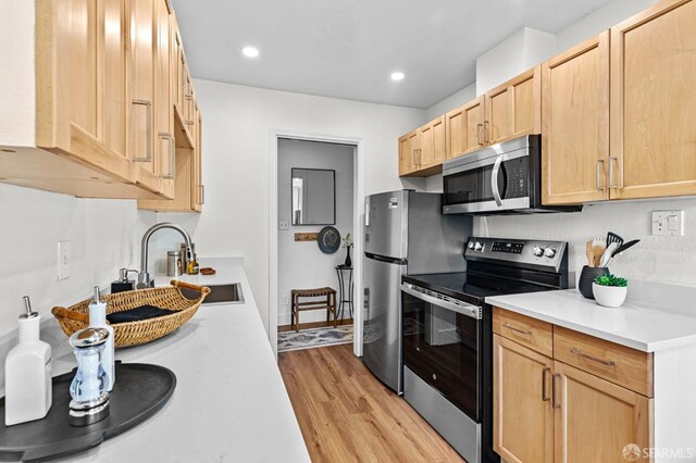 kitchen featuring stainless steel appliances, sink, light brown cabinets, and light hardwood / wood-style floors