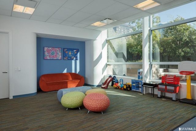 interior space with a paneled ceiling and dark colored carpet