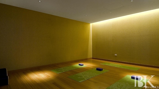 unfurnished room with baseboards, wood finished floors, and golf simulator