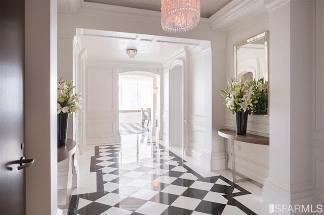 hallway with ornamental molding and an inviting chandelier