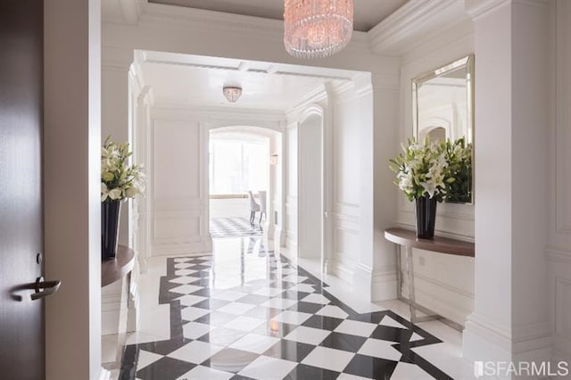 hall with ornamental molding, arched walkways, a notable chandelier, and decorative columns