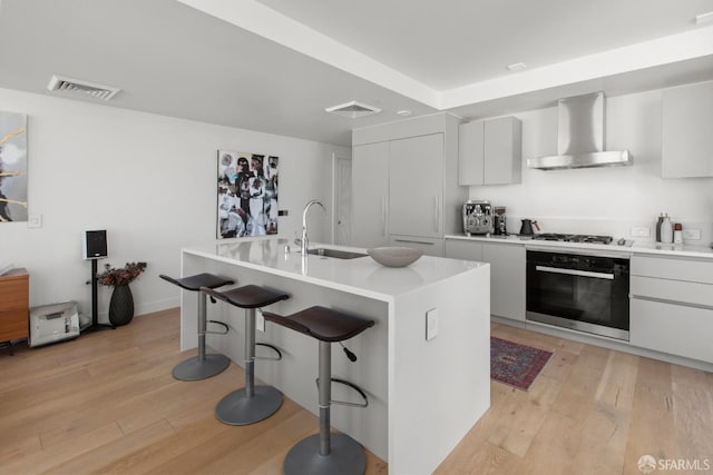 1545 Pine St Unit 1201, San Francisco, CA 94109 - kitchen with oven, wall chimney exhaust hood, modern cabinets, a kitchen breakfast bar, and light wood finished floors