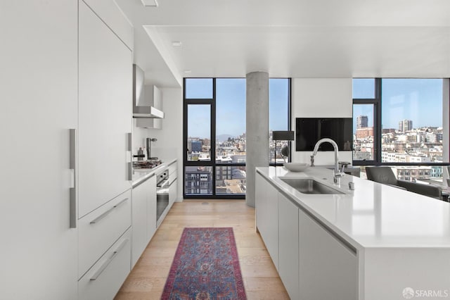 1545 Pine St Unit 1201, San Francisco, CA 94109 - kitchen featuring modern cabinets, expansive windows, wall chimney range hood, appliances with stainless steel finishes, and white cabinetry