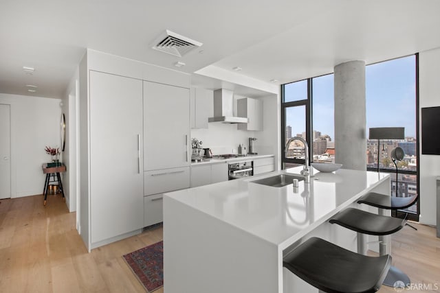 1545 Pine St Unit 1201, San Francisco, CA 94109 - kitchen with wall chimney range hood, modern cabinets, light wood-type flooring, light countertops, and white cabinetry