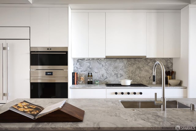 kitchen featuring light stone counters, white cabinets, and stainless steel double oven