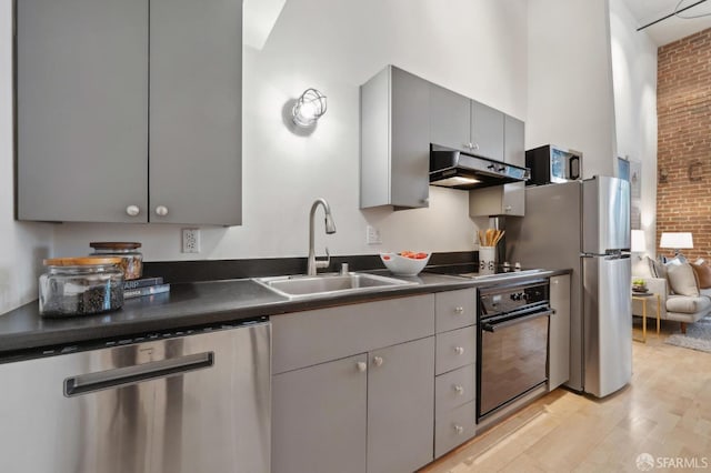 kitchen with gray cabinetry, black appliances, dark countertops, and under cabinet range hood