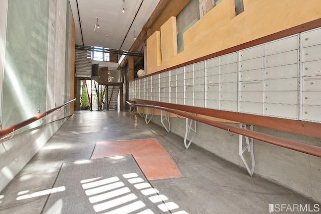 hallway featuring concrete floors, a towering ceiling, and mail area