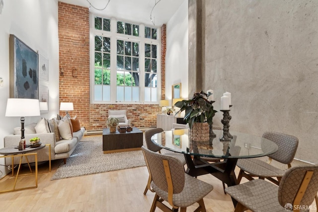 interior space featuring a baseboard heating unit, brick wall, a high ceiling, and wood finished floors